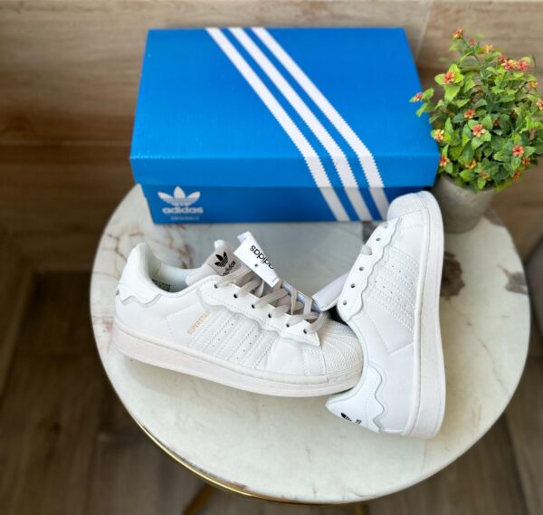 "Adidas Superstar Cappuccino Off White sneaker with a stylish off-white upper and iconic three stripes design.