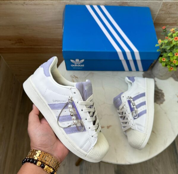 "Side profile of Adidas Superstar Chain sneakers, showcasing the iconic three-stripe design and premium craftsmanship."